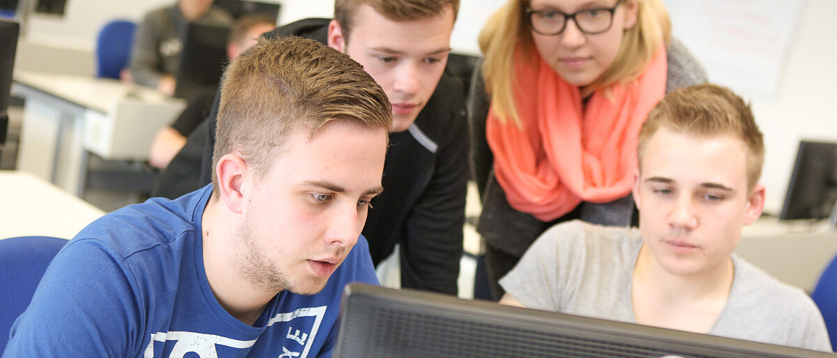 Seminarteilnehmer am PC. Seminarteilnehmer schauen zusammen in einen PC-Bildschirm.