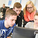 Seminarteilnehmer schauen zusammen in einen PC-Bildschirm.