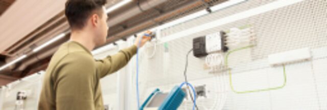 Meisterschüler steht in der Werkstatt vor einer Schaltwand 