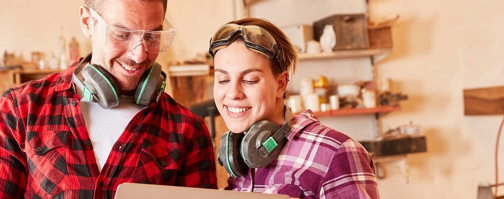 Junge Handwerker schauen auf Laptop